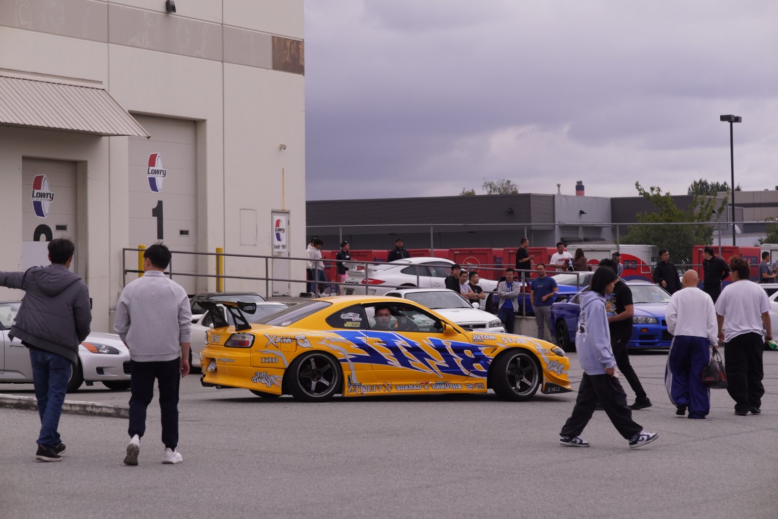 People gathered around a yellow sports car at a car meet