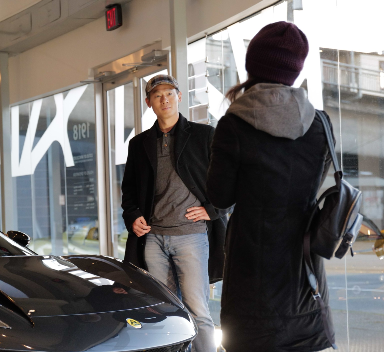 Two people in conversation beside a sports car in a showroom
